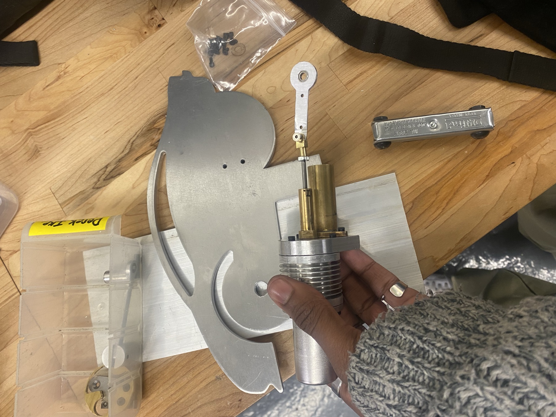 Machined components: bedplate, brass power cylinder, and hardware, held during assembly